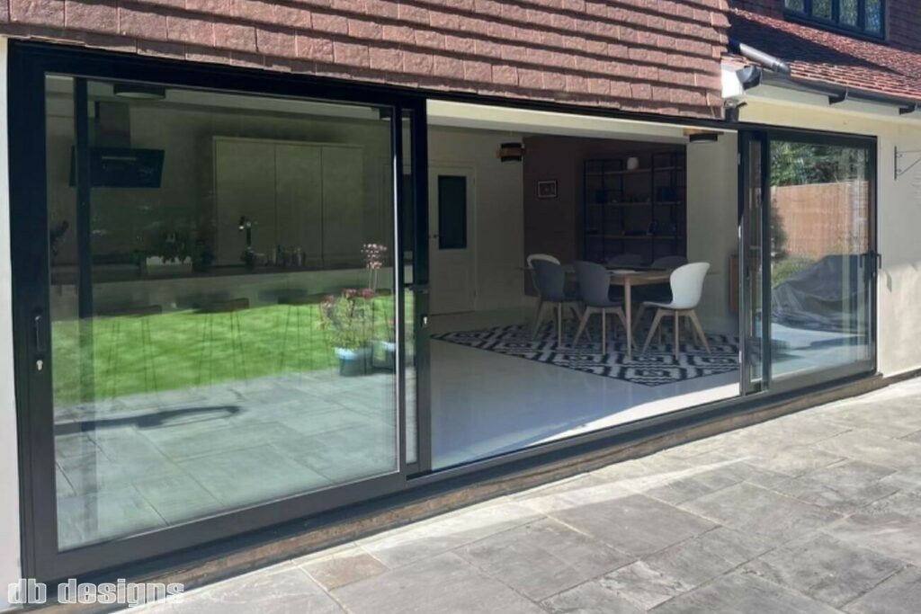 The rear of a home showing a large, four pane sliding patio door set with sleek black powder-coated aluminium frames.